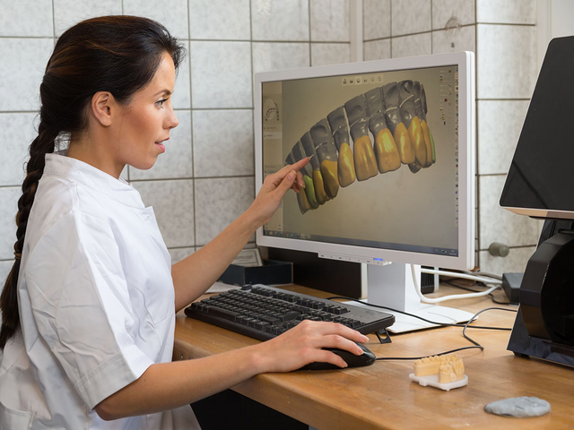 Dental technician reviewing a digital restoration design on a monitor