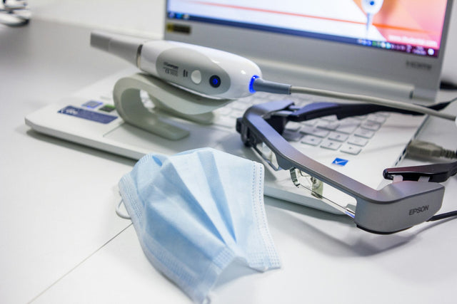 Intraoral scanner on a desk next to a laptop
